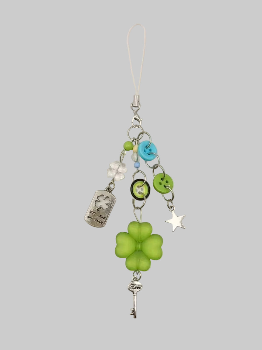Phone charm with green clover, key, and star on a beige background